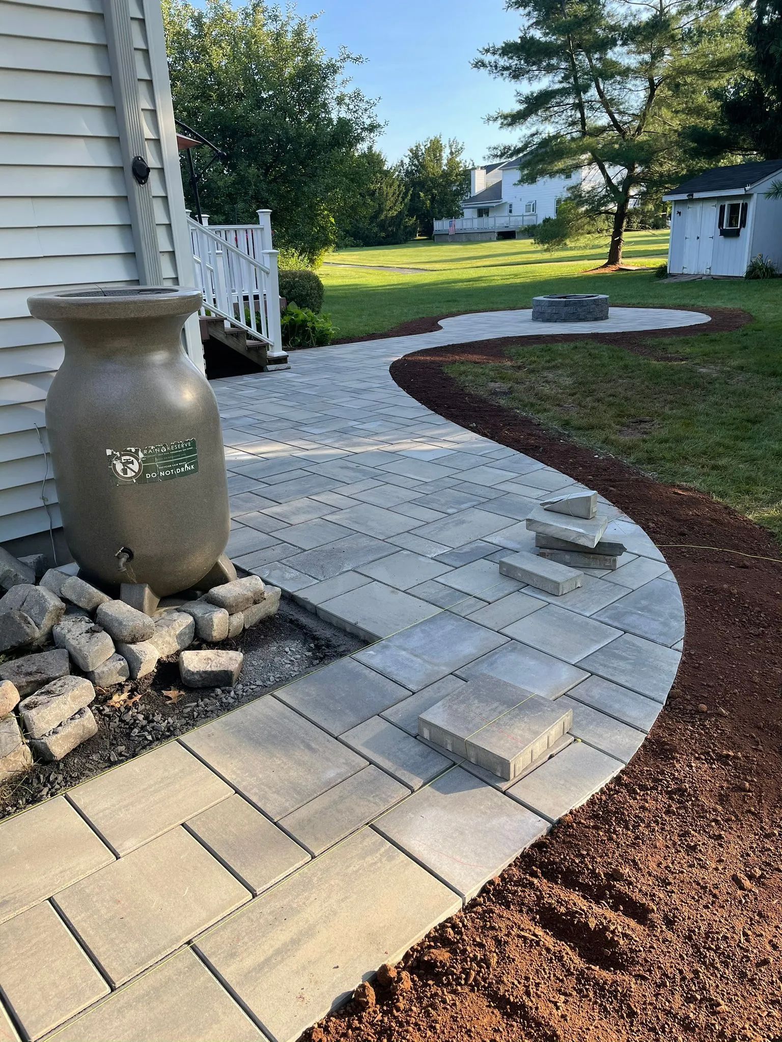 A brick walkway leading to a house with a vase on the side of it.