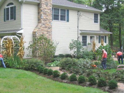 A group of people are working in front of a house