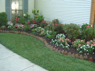 A lawn with flowers and bushes in front of a house