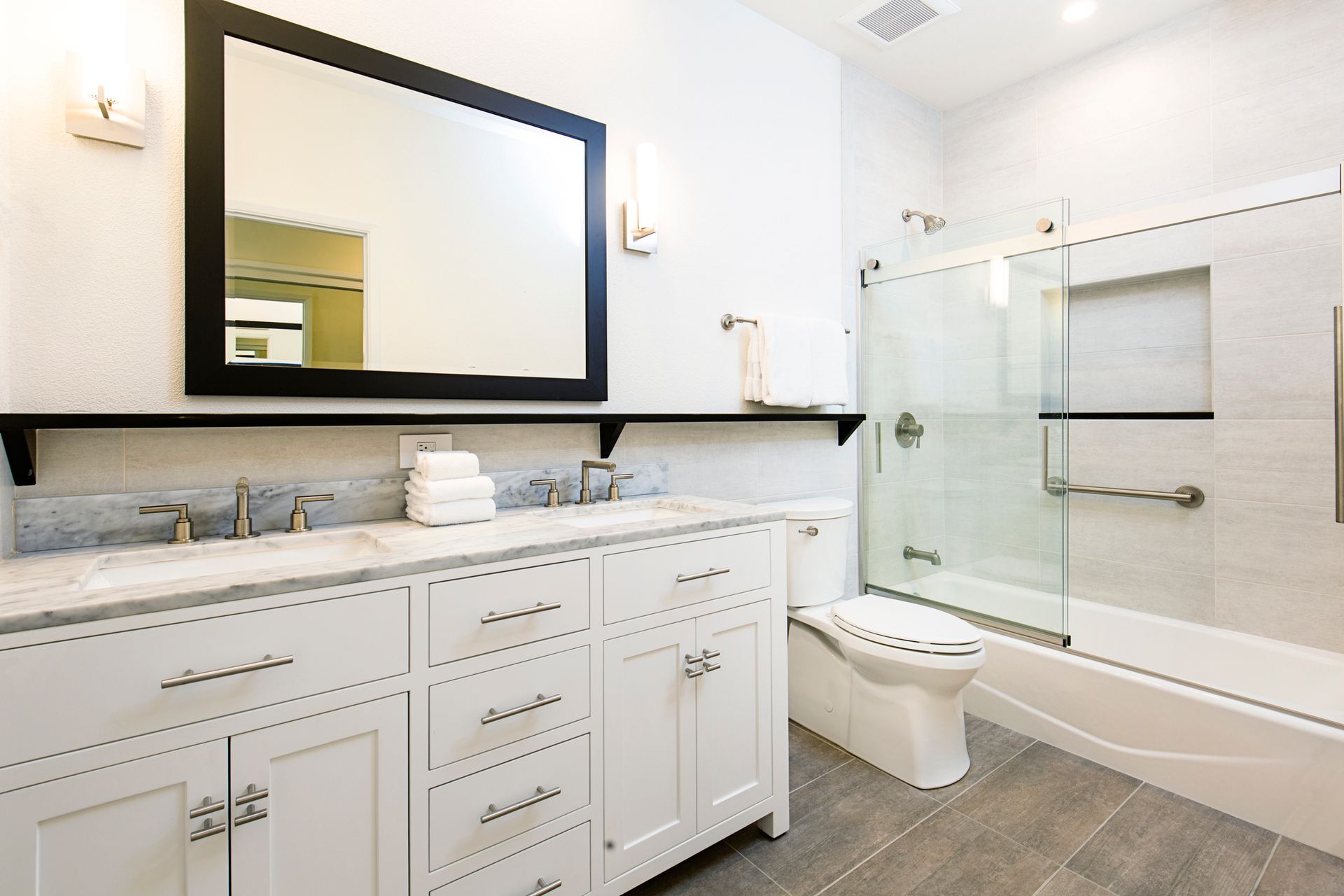 A bathroom with two sinks , a toilet , and a shower.