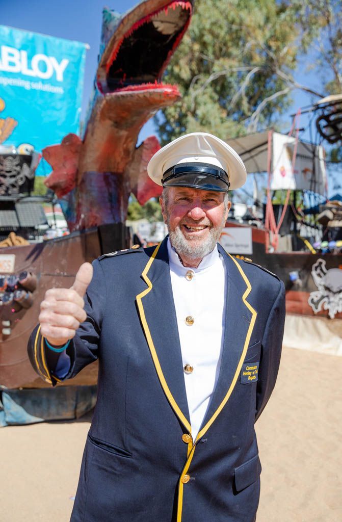 A man in a suit and hat is giving a thumbs up