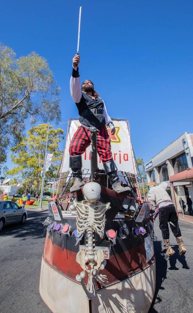 A man in a pirate costume is standing on top of a pirate ship.