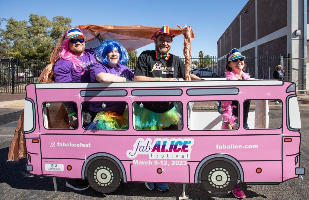 A group of people are sitting in a pink bus.