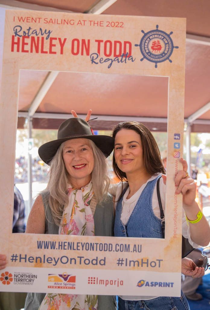Two women are standing next to each other holding a picture frame.
