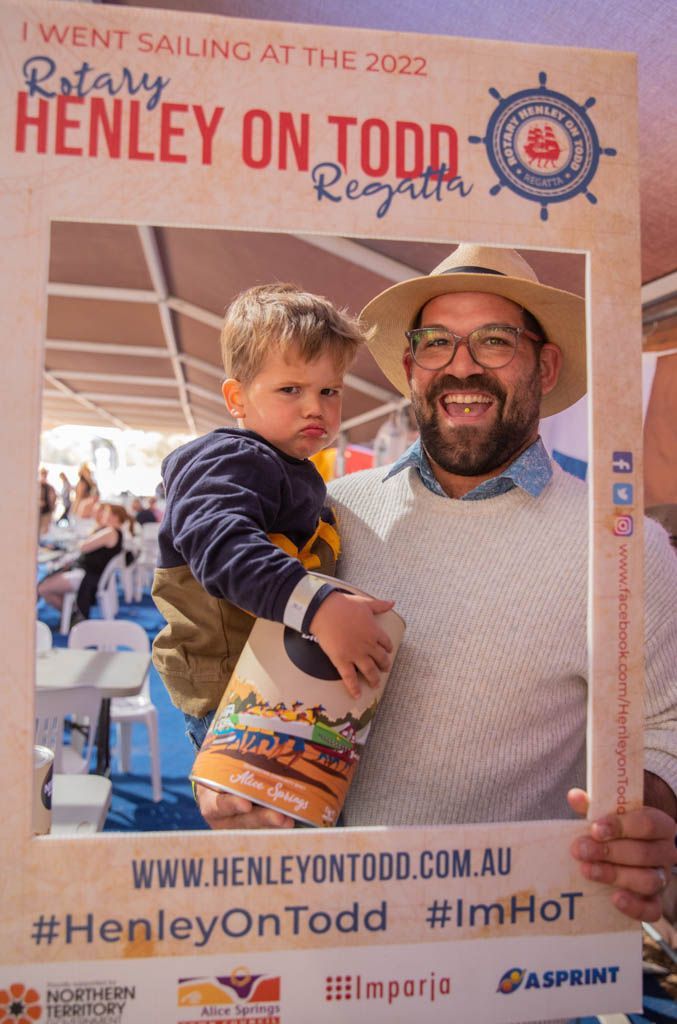 A man is holding a child in front of a sign that says i went sailing at the 2022