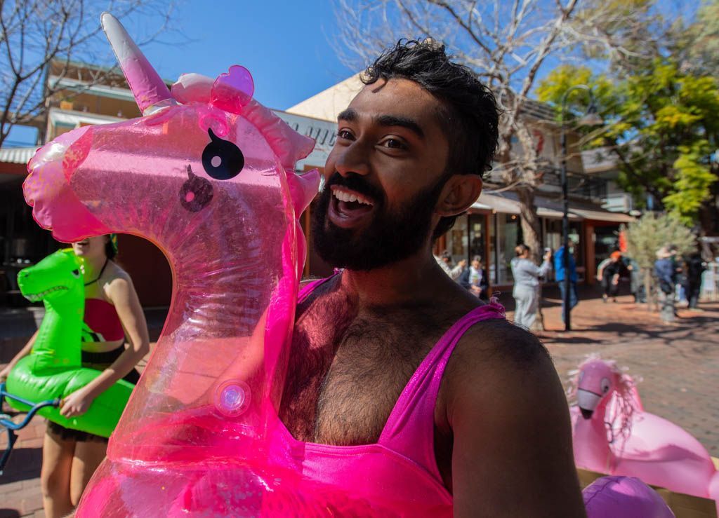 A man with a beard is holding a pink inflatable unicorn.
