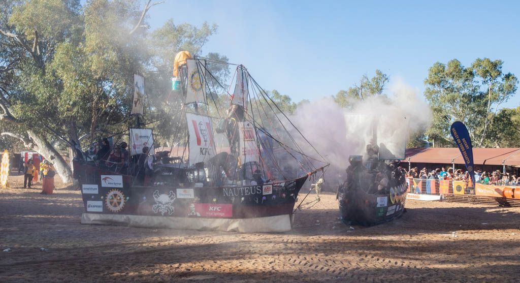 A car is driving down a dirt road with smoke coming out of it.