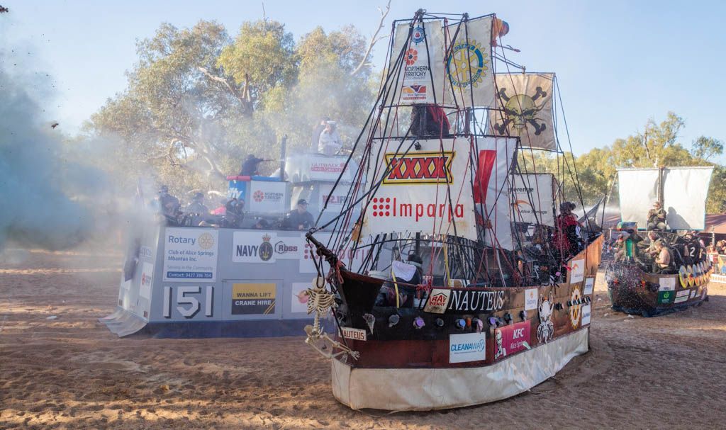 A large pirate ship is being built in the middle of a dirt field.