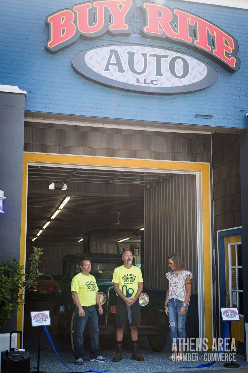 A group of people standing in front of a building that says buy rite auto