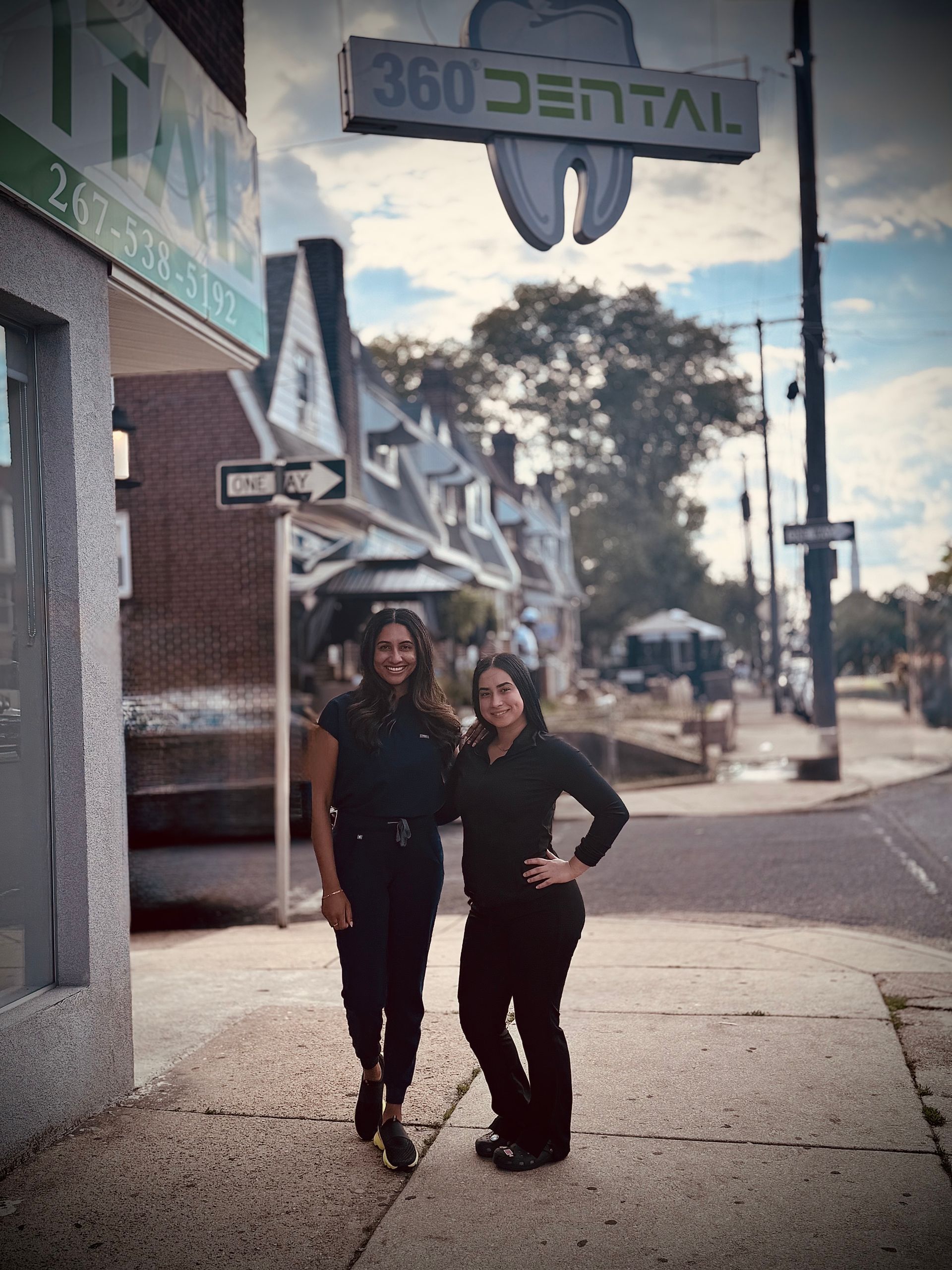 Two women are posing for a picture in front of a wall with pictures of teeth on it.