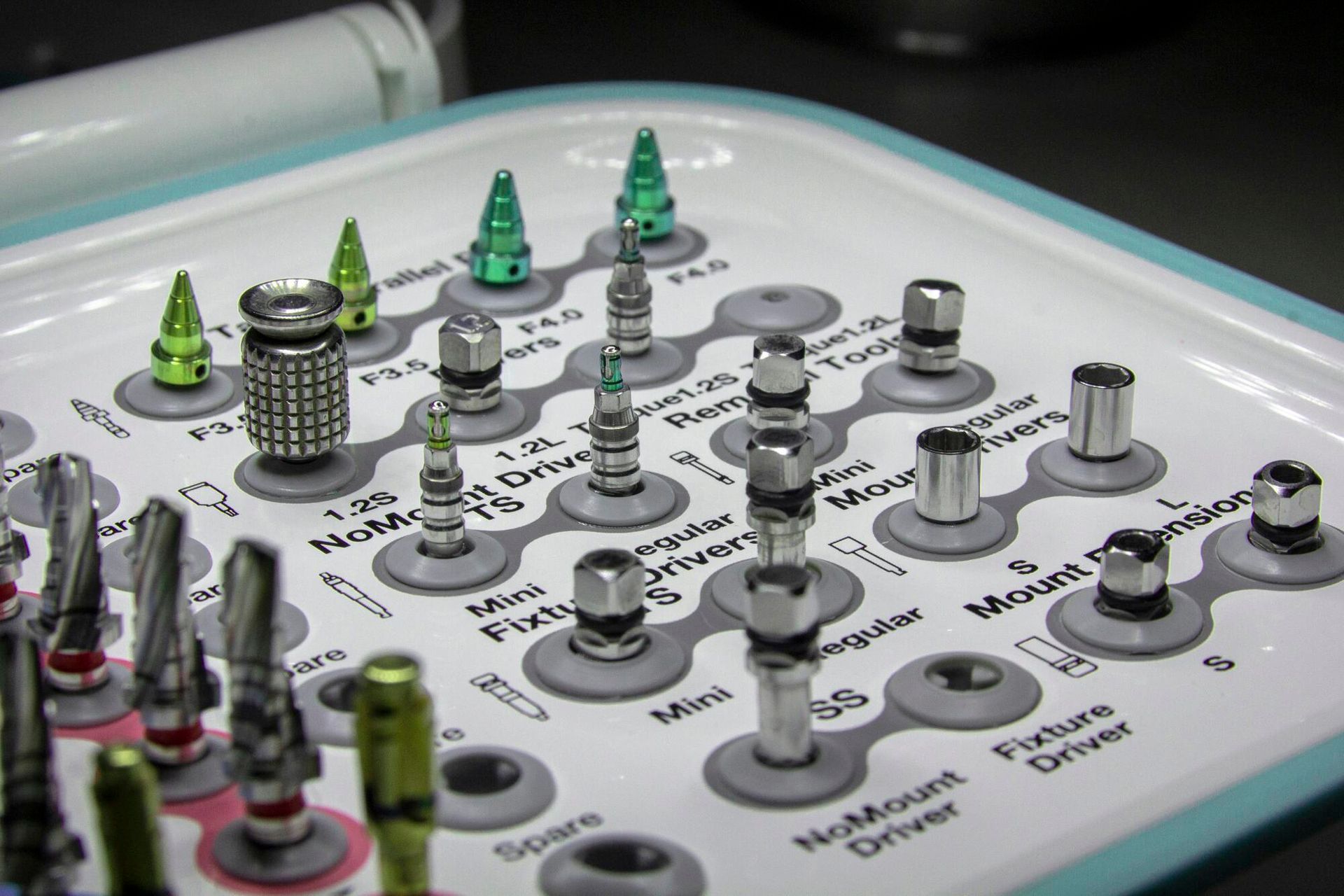 Close-up of a control panel with knobs and green-topped switches on a white surface