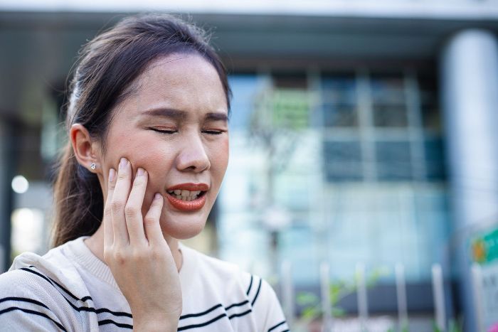 A woman is holding her face in pain because of a toothache.