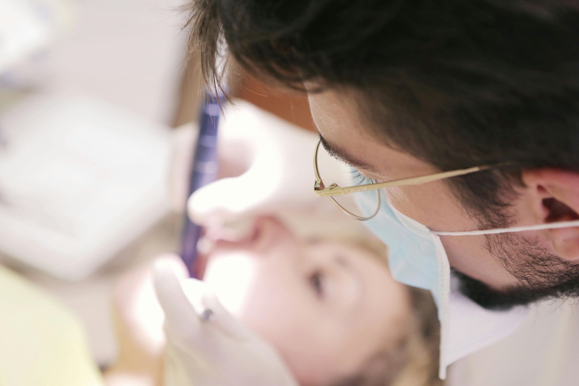 A woman is looking at her teeth in a mirror.