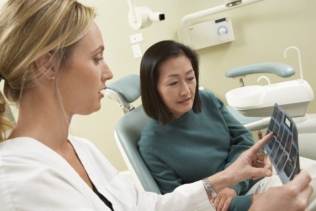 A dentist is looking at an x-ray of a patient 's teeth.