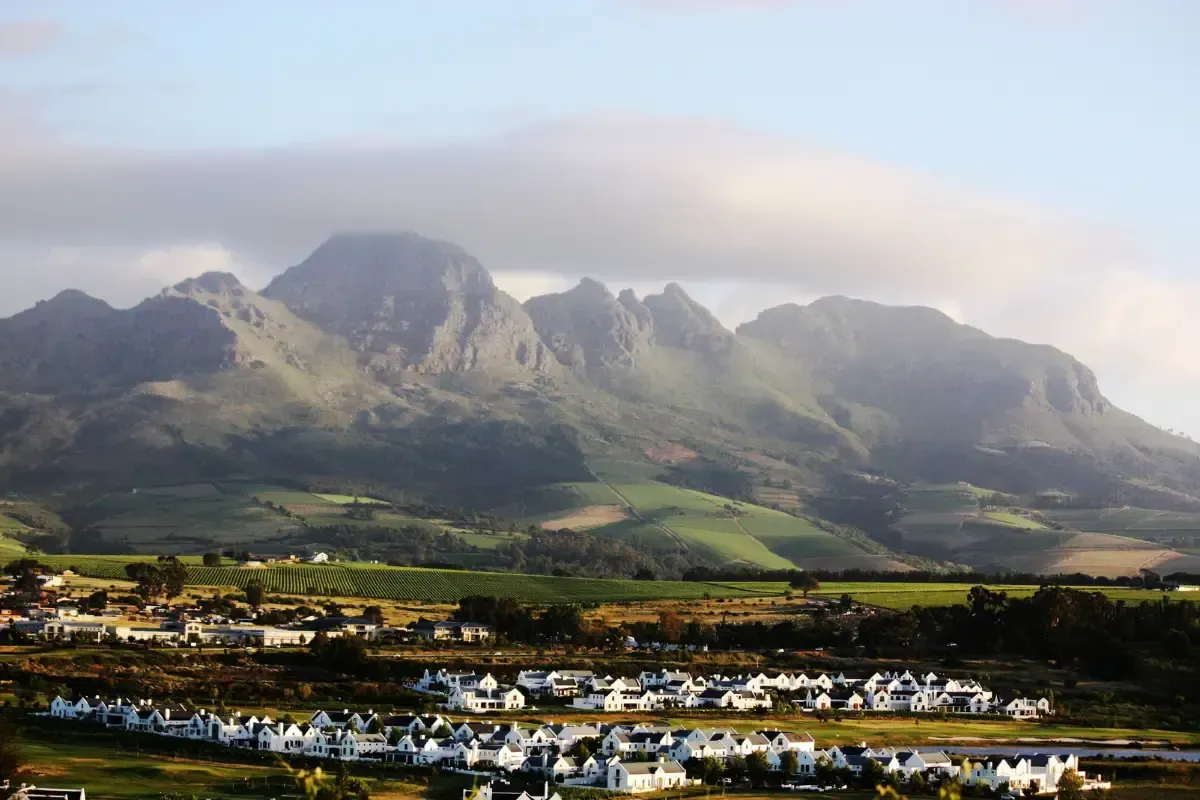 Mountain range above a green valley with a small town under a cloudy sky