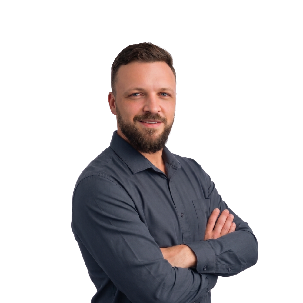Smiling person with folded arms wearing a dark gray shirt on a white background