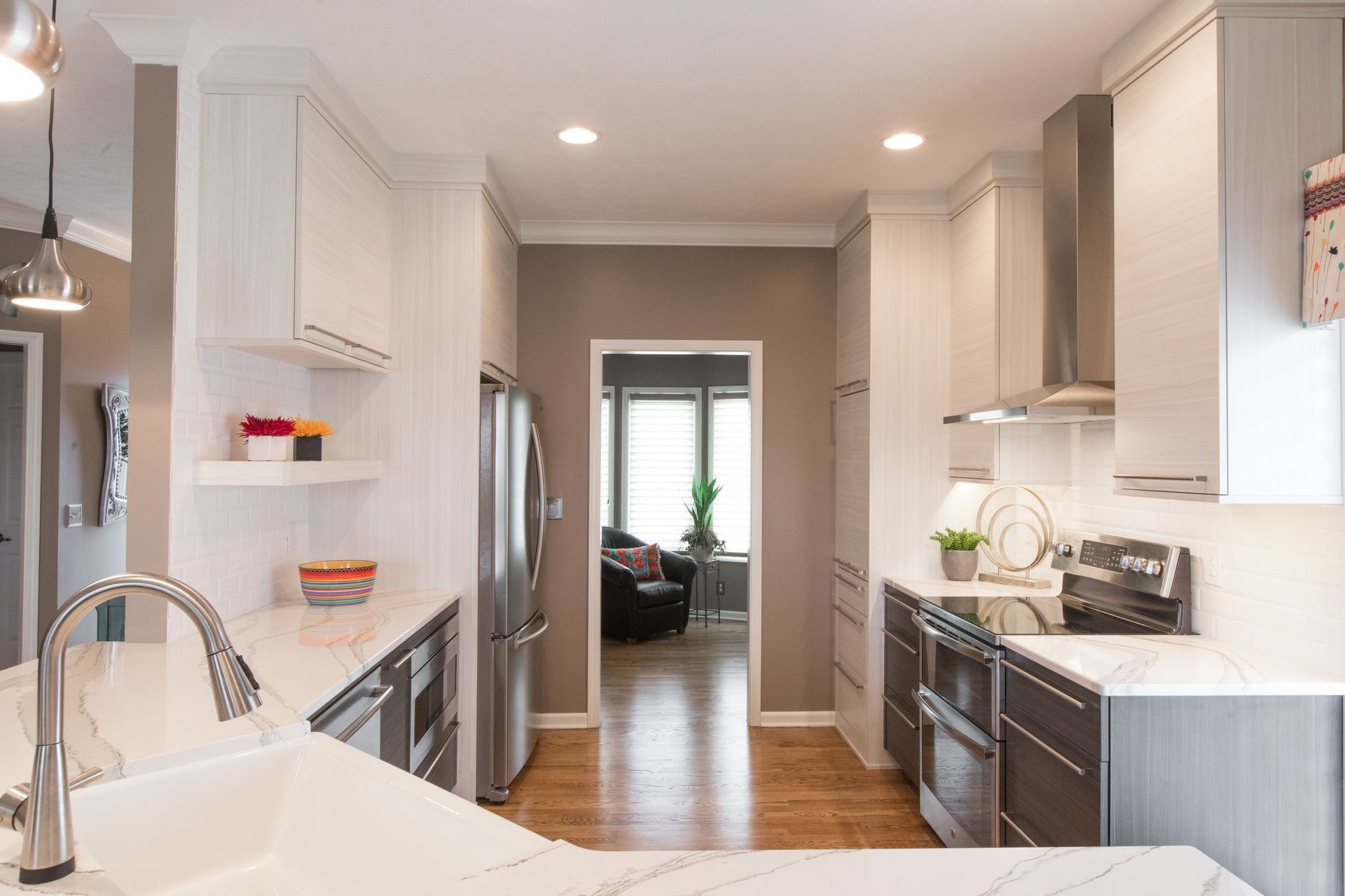 A kitchen with white cabinets , stainless steel appliances , a sink , and a refrigerator.