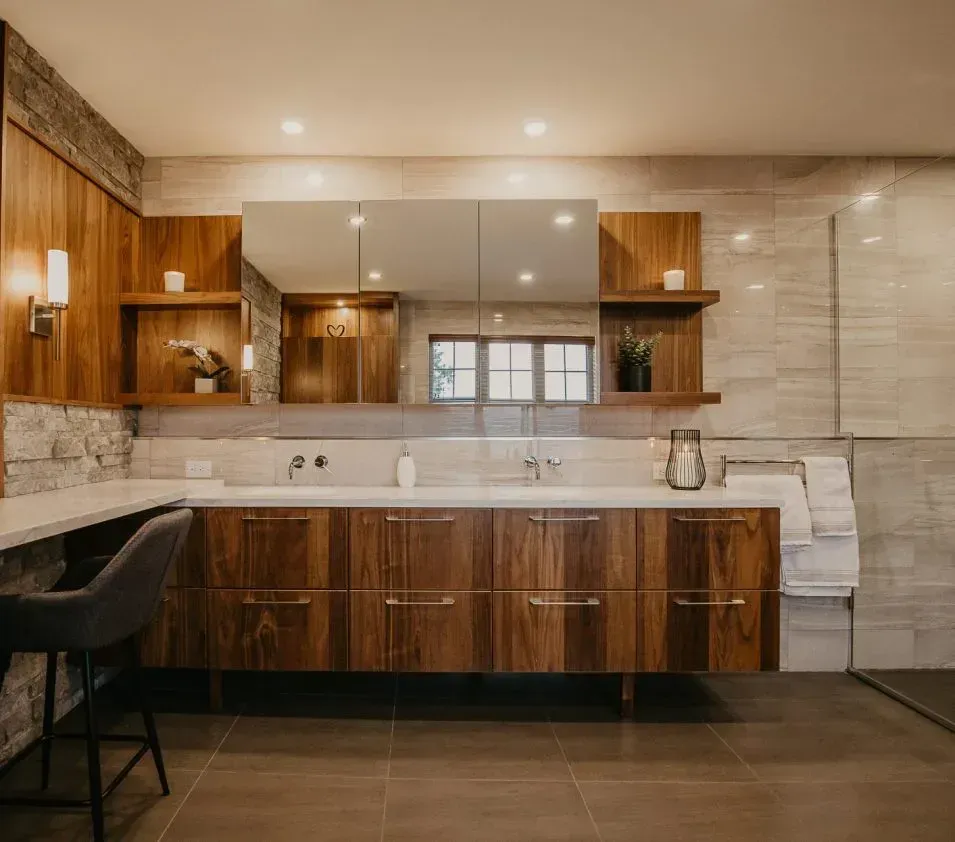 A bathroom with a sink , mirror and wooden cabinets.