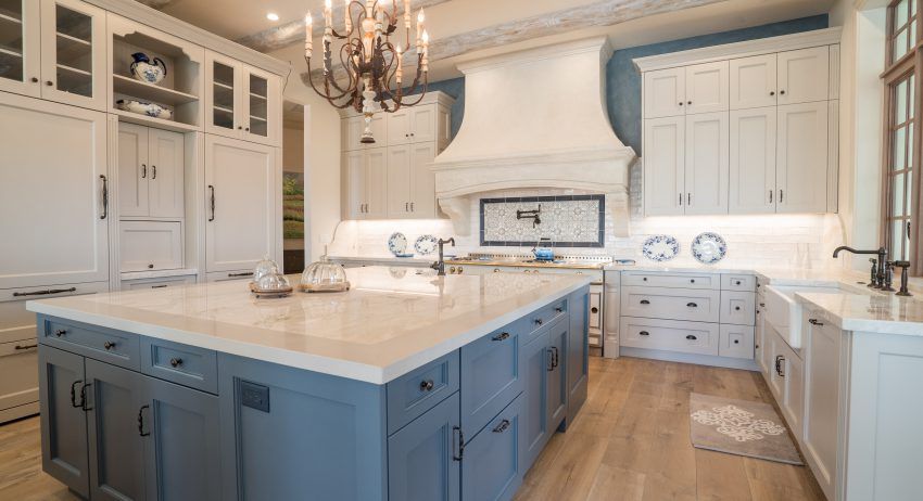 A kitchen with white cabinets and a large island in the middle.