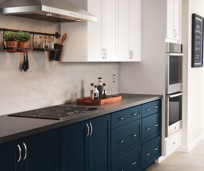 A kitchen with blue cabinets and white cabinets has a stove top oven.