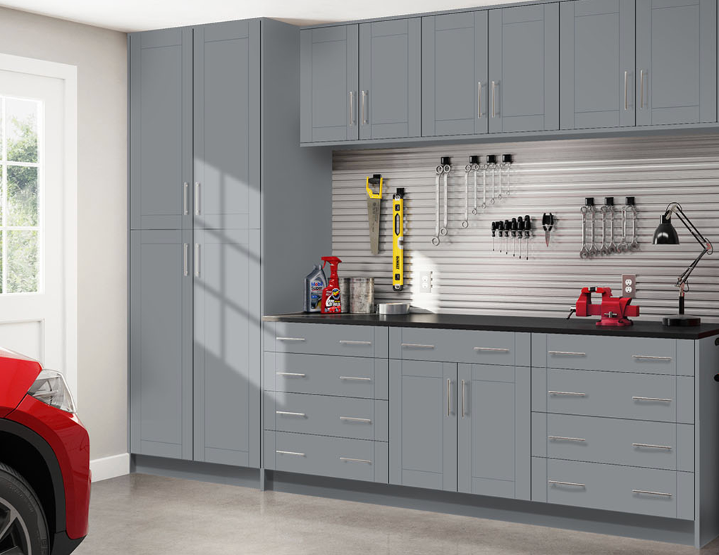 A red car is parked in a garage with lots of cabinets and drawers.