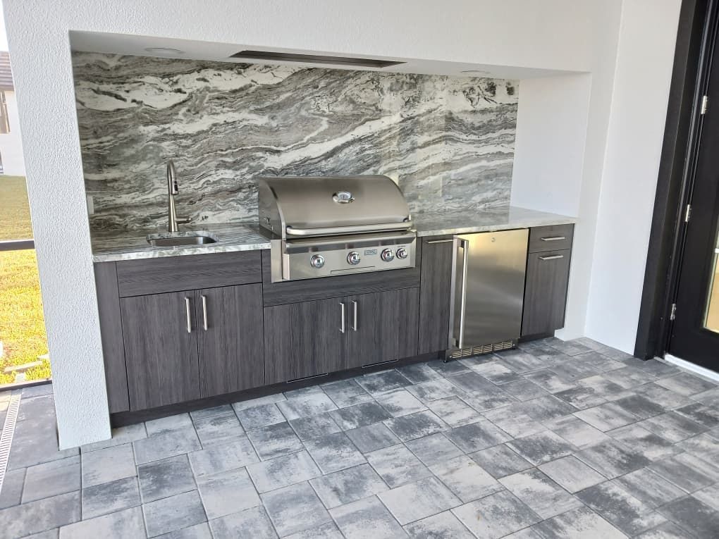 A kitchen with a grill , sink , and refrigerator.