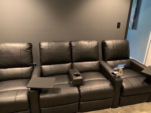 A row of black leather recliner chairs in a home theater