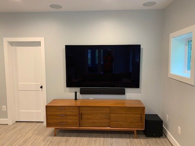 A flat screen tv is mounted on the wall above a wooden entertainment center