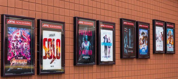 A row of movie posters hanging on a wall at a movie theater.