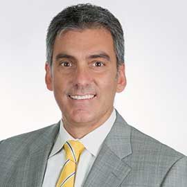 Professional headshot of Emmanuel Calligeris in a gray suit and yellow striped tie on a white background