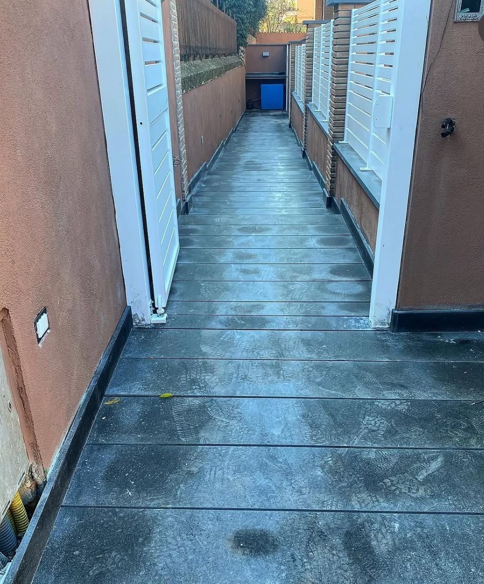 Piccola piscina blu bordata di bianco, circondata da ghiaia e alte siepi verdi all’aperto