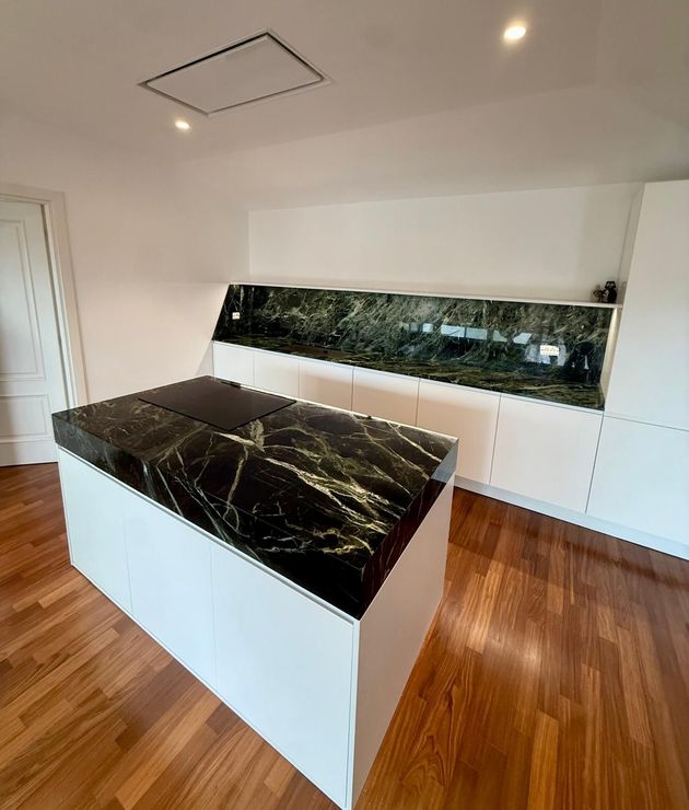 Isola da cucina in marmo nero con base bianca e piano scuro coordinato in un ambiente moderno