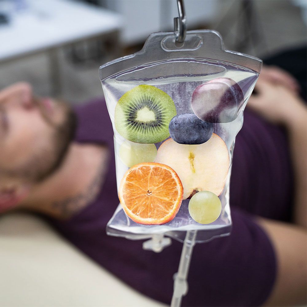 A man is laying on a bed with a bag of fruit hanging from his neck.