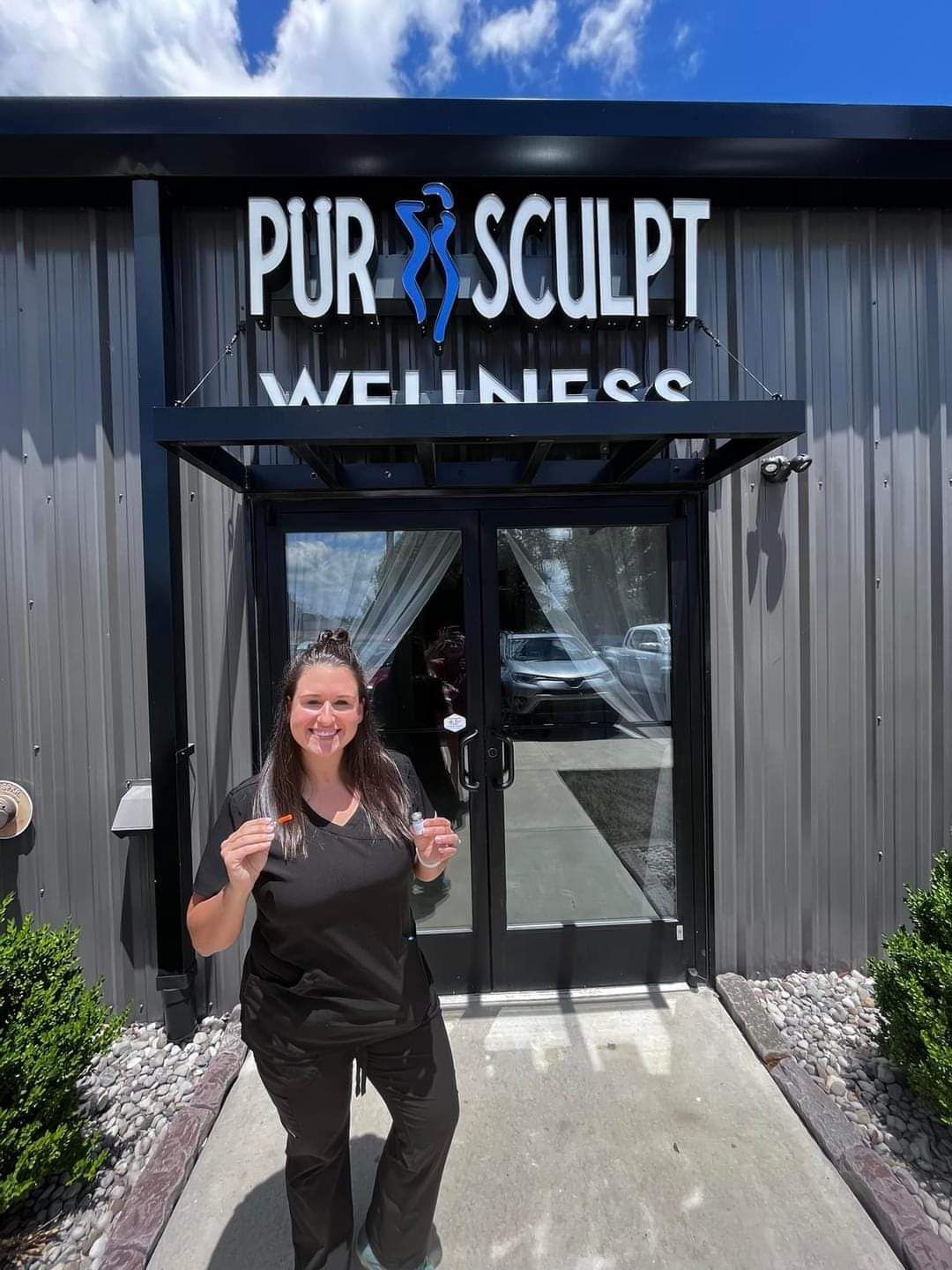 A woman is standing in front of a building with a sign that says pur sculpt wellness.