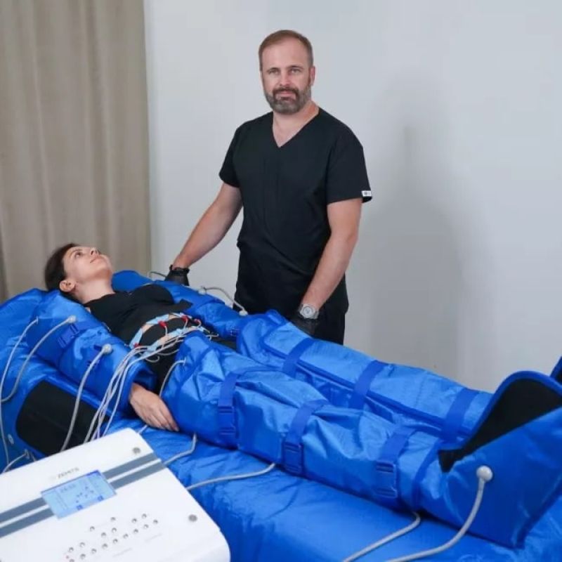 A man stands next to a woman laying on a blue blanket