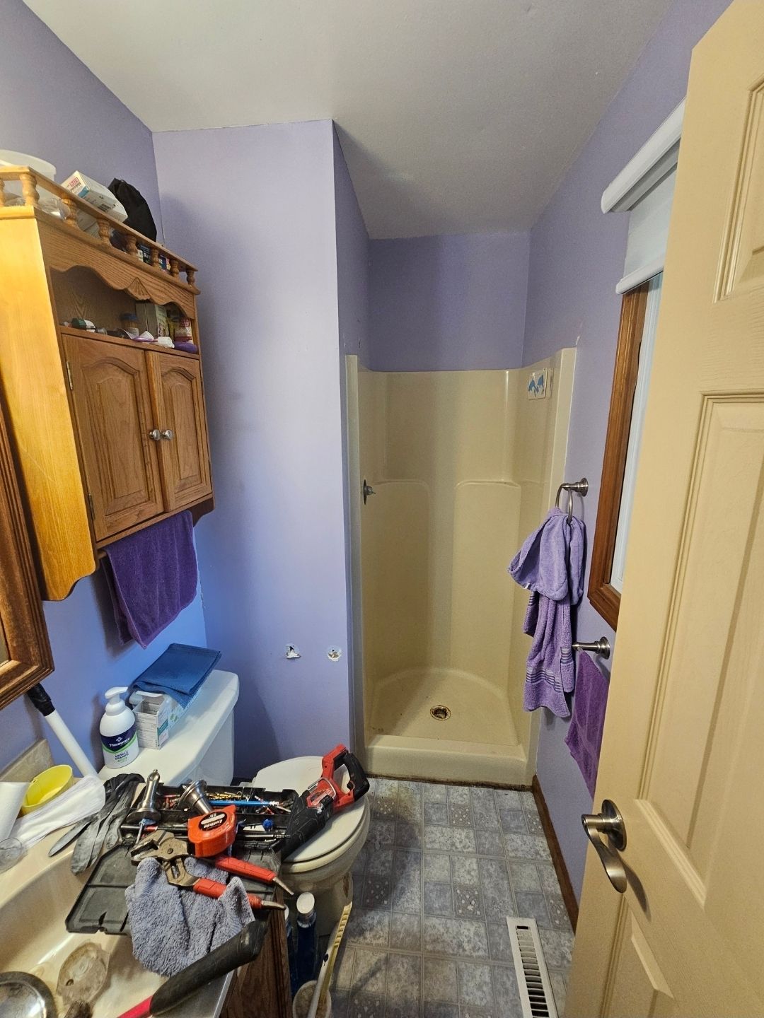 Bathroom with a white vanity, mirror, and stained floor.