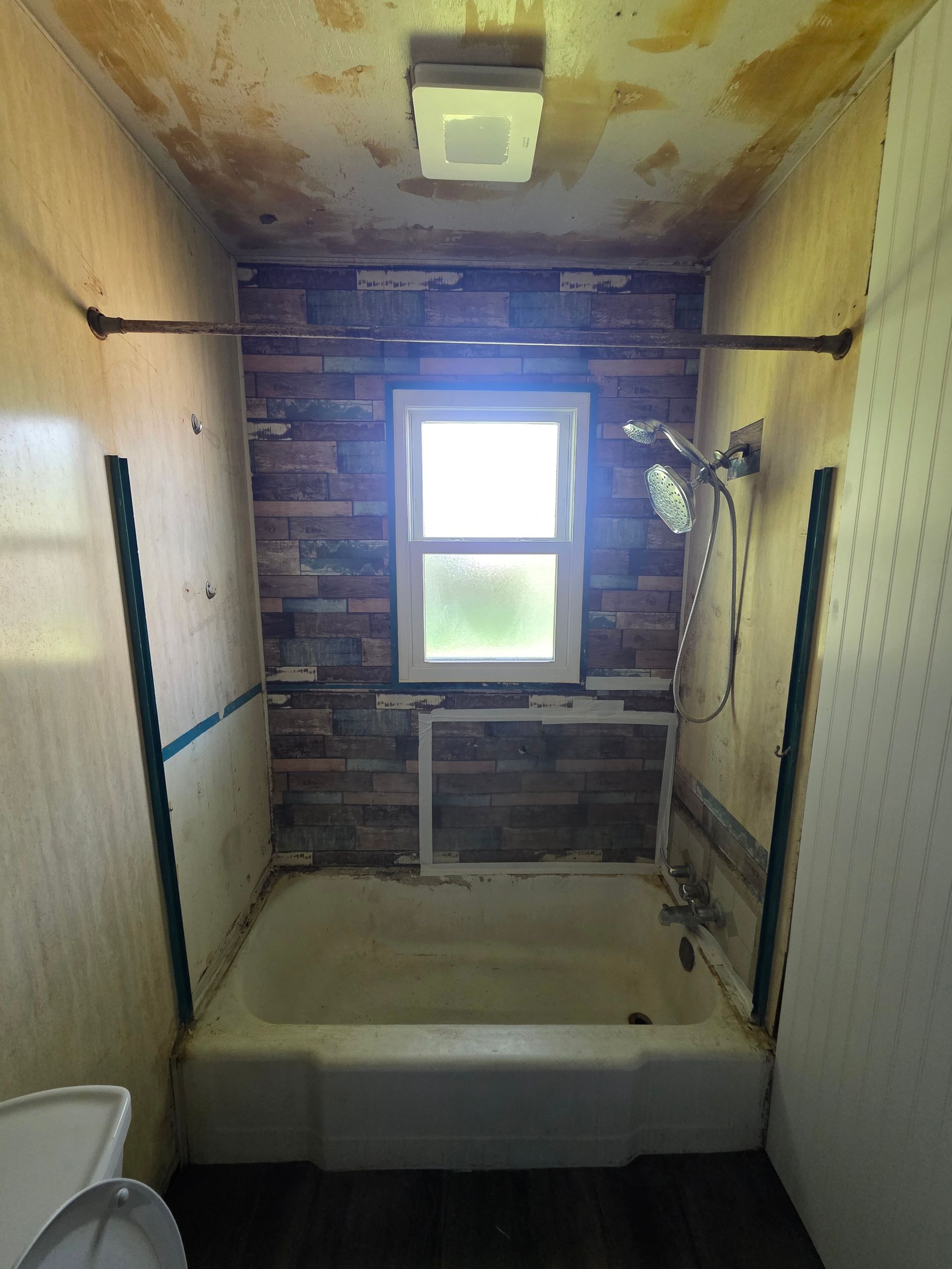 Bathroom with a white tub, toilet, and vanity, and a large mirror. Brown floor.
