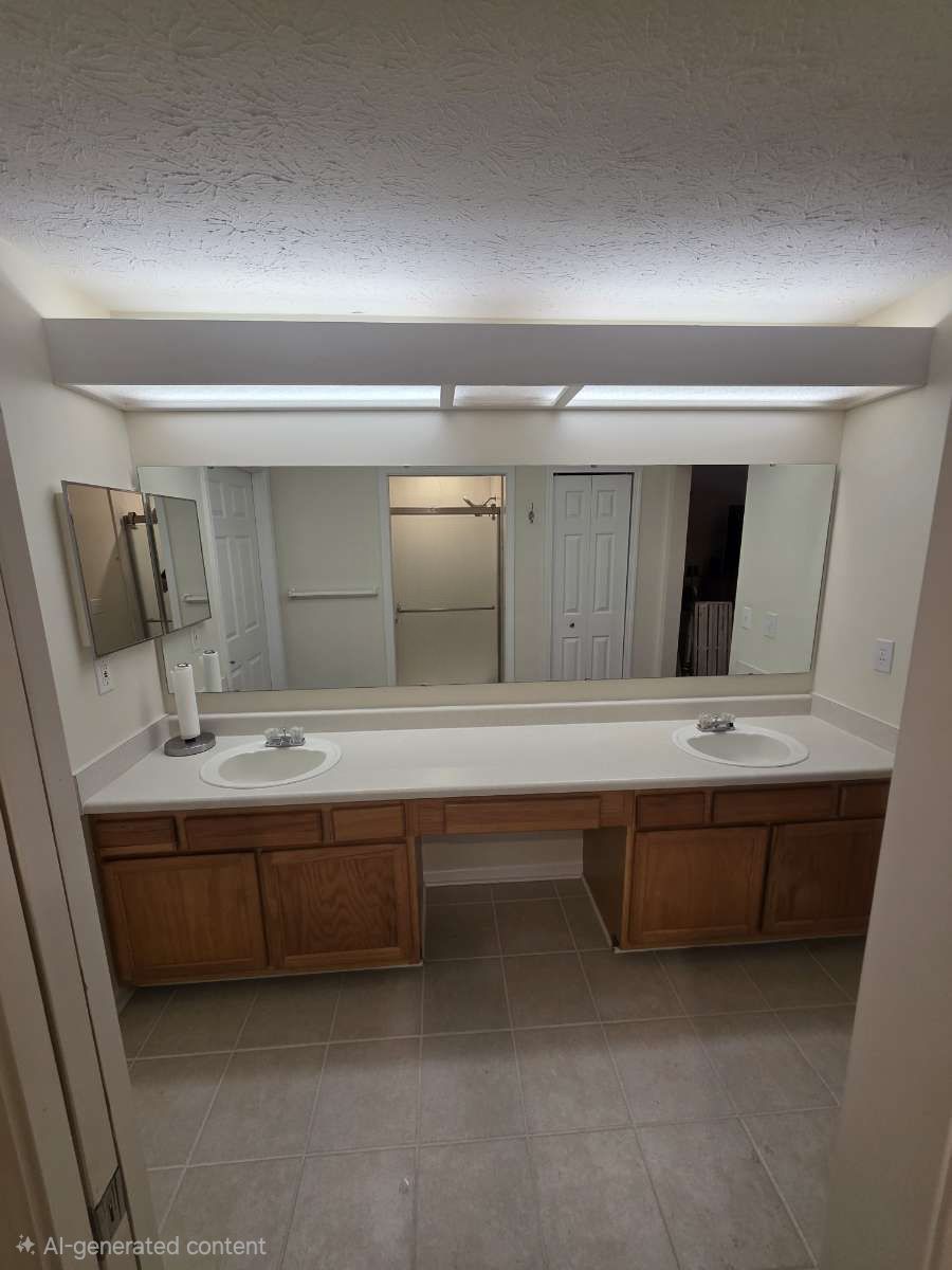 Bathroom with a white tub, toilet, and vanity, and a large mirror. Brown floor.