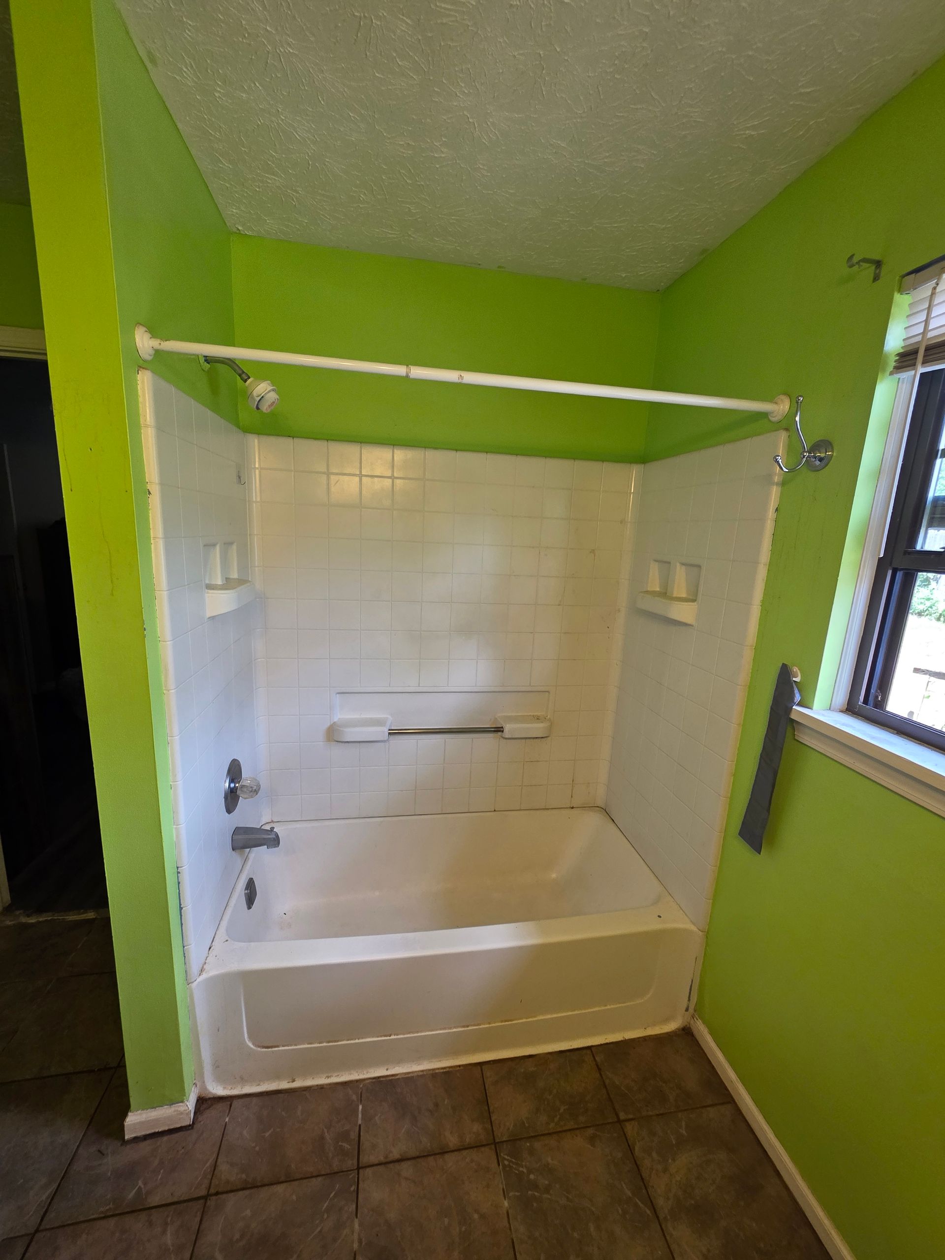 Accessible bathroom with a walk-in tub, white tile walls, lime green walls, and brown tiled floor