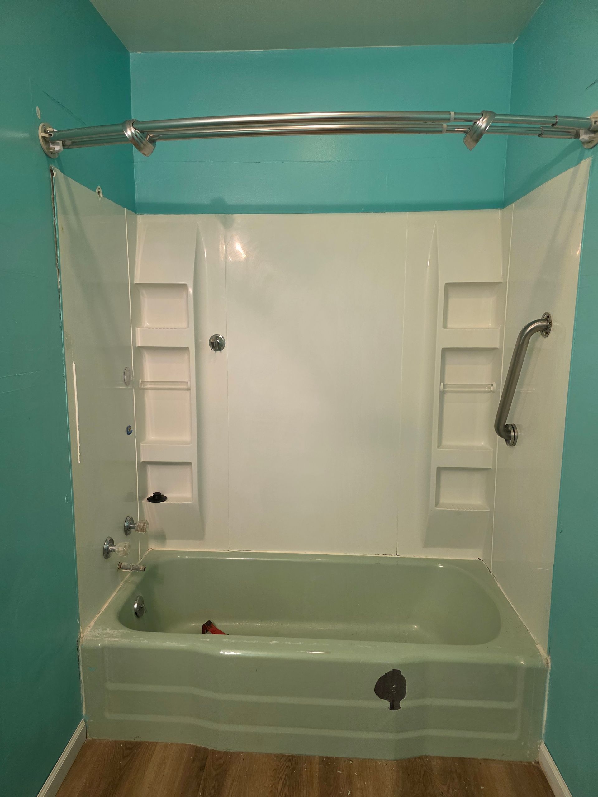 Accessible bathroom with pale green walk-in tub, white shower walls, and chrome grab bars