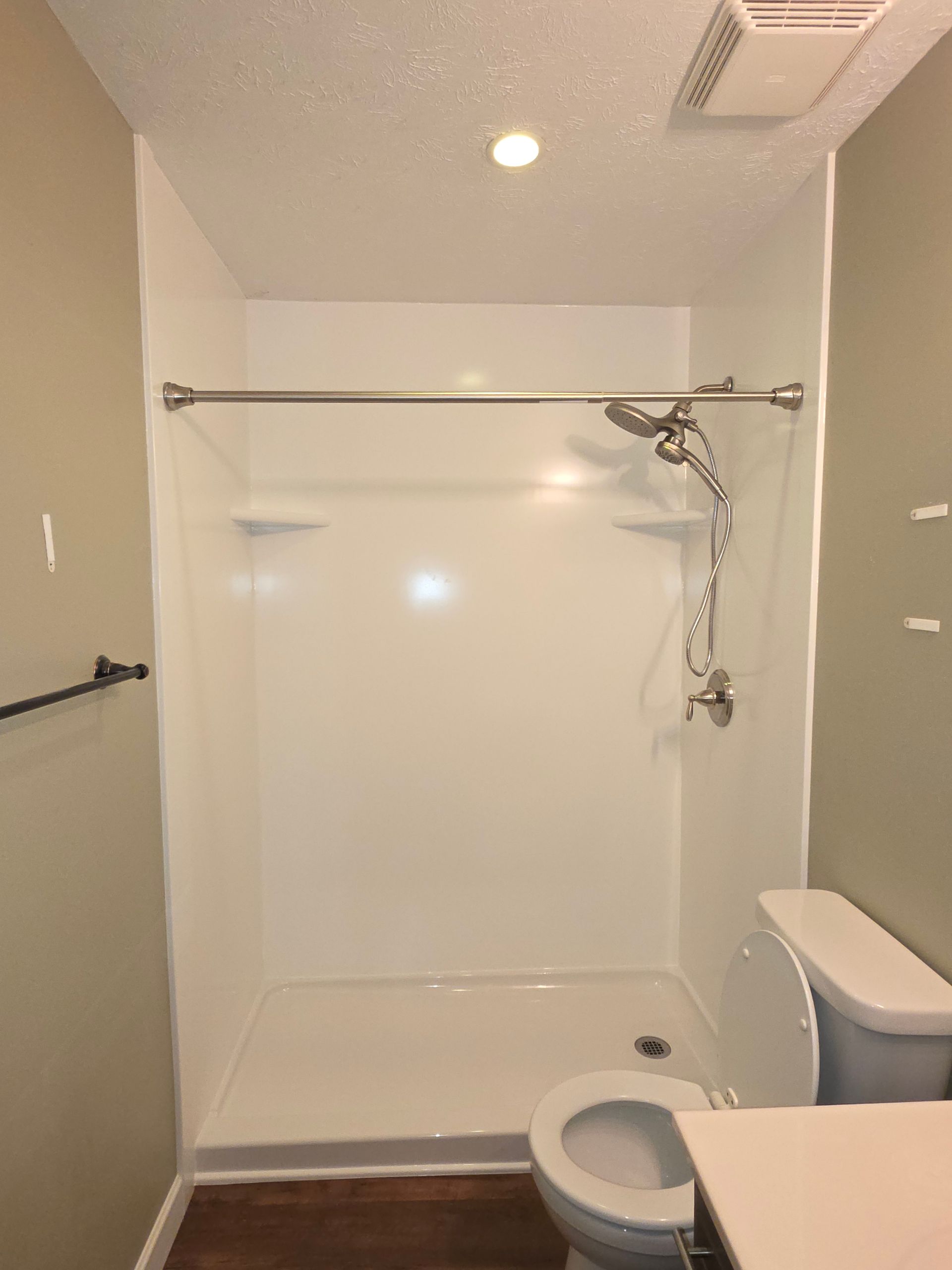 Small bathroom with a walk-in shower, toilet, and shower curtain rod.
