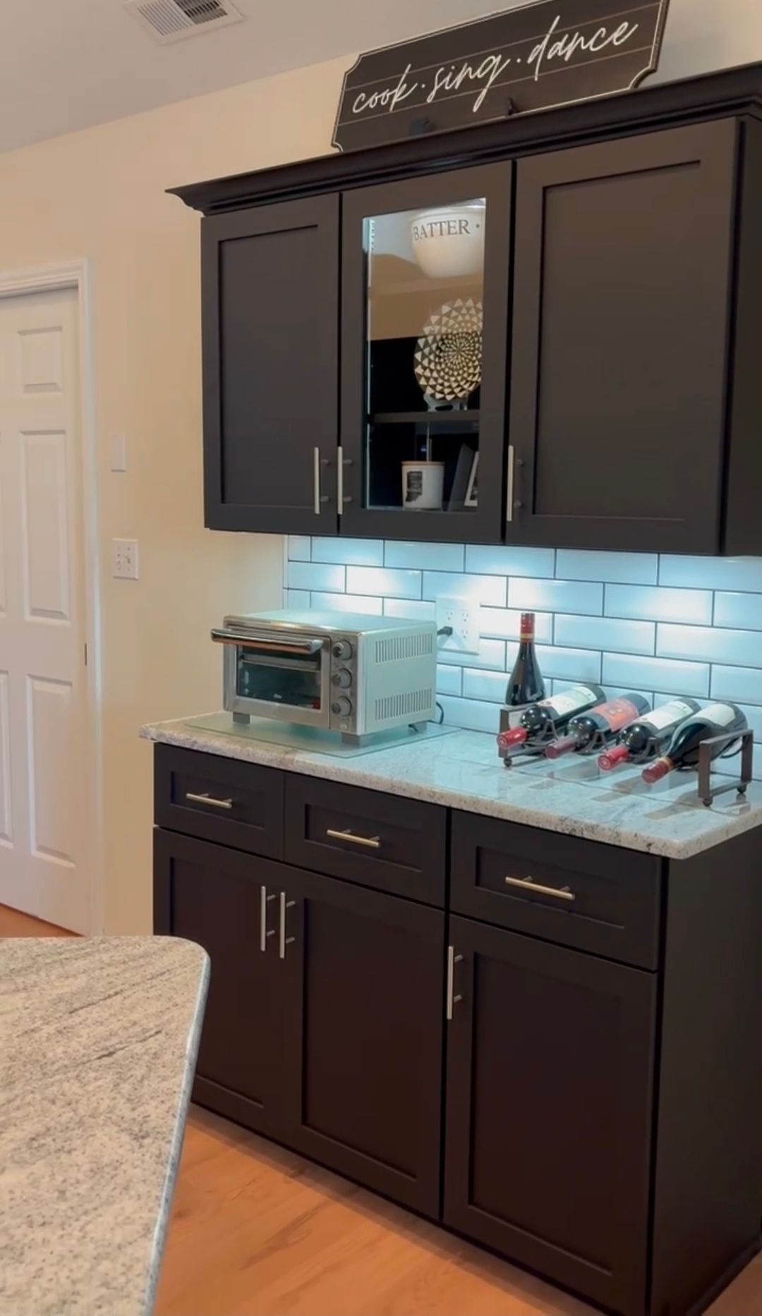 Dark kitchen cabinets with a countertop, toaster oven, and wine rack.