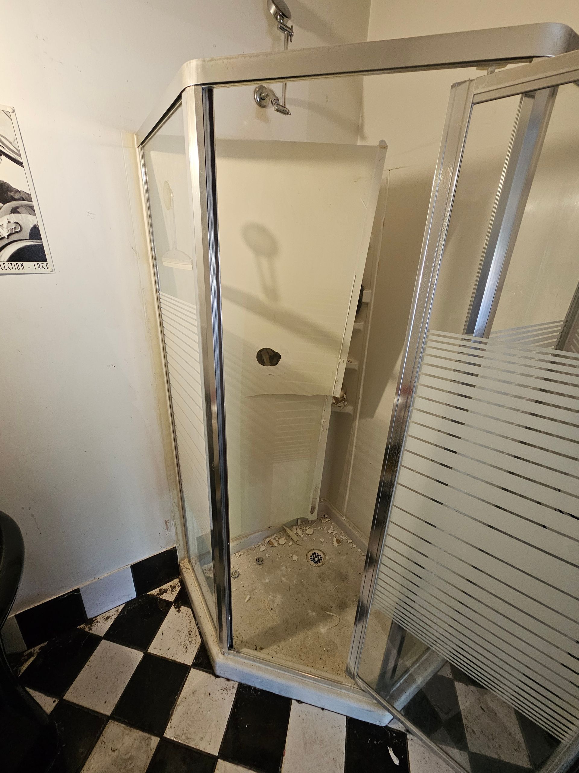 A shower stall with the door open, in a room with black and white checkered tiles.