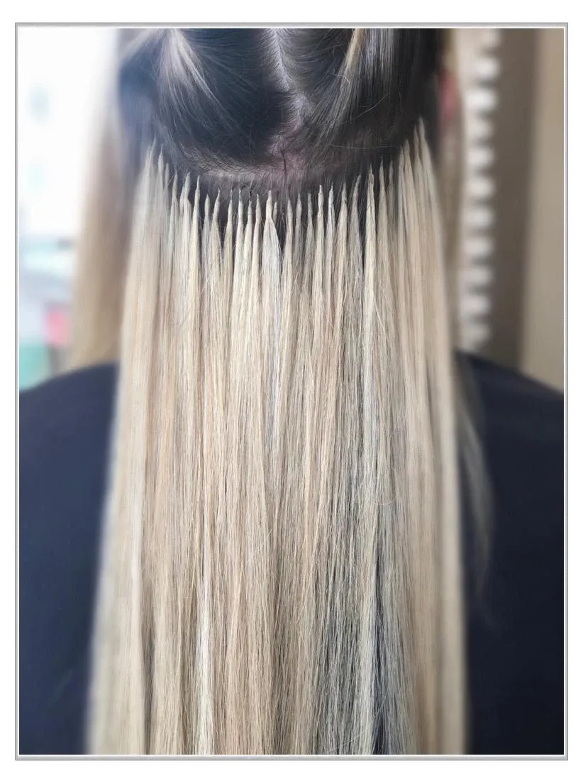 Nahaufnahme von langem, blondem Haar mit dunklem Ansatz, das vor einem dunklen Hintergrund glatt herabhängt.