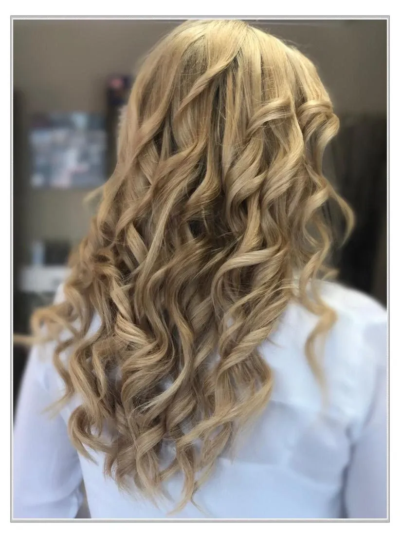 Blonde, gewellte, halb hochgesteckte Frisur mit lockeren Locken, von hinten in einem Salon gesehen
