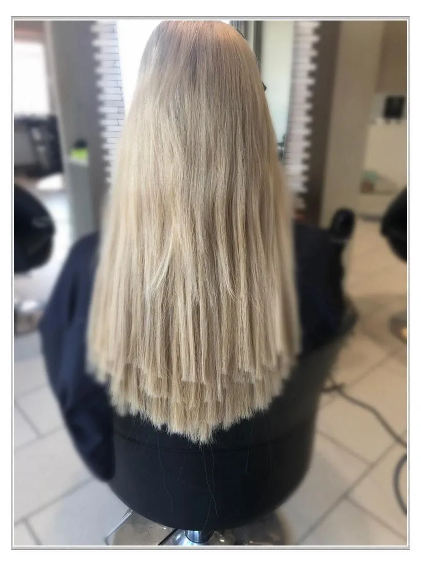 Blondes, gestuftes Haar mit stumpfen Spitzen, von hinten in einem Friseurstuhl gesehen