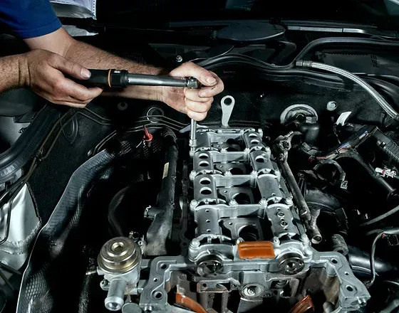 Monteur gebruikt een sleutel op een motor en werkt aan de cilinderkop.