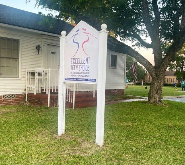 A sign for excellent teen choice is in front of a white house.