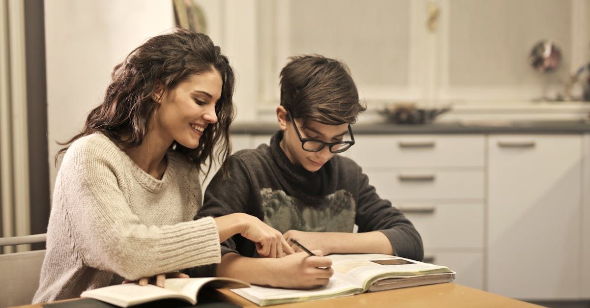 A woman is helping a boy with his homework at a table.