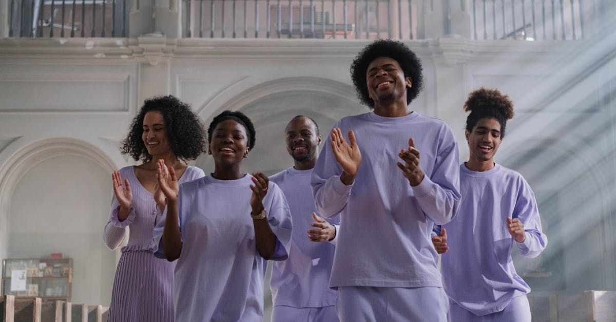 A group of people in purple shirts are dancing together in a room.
